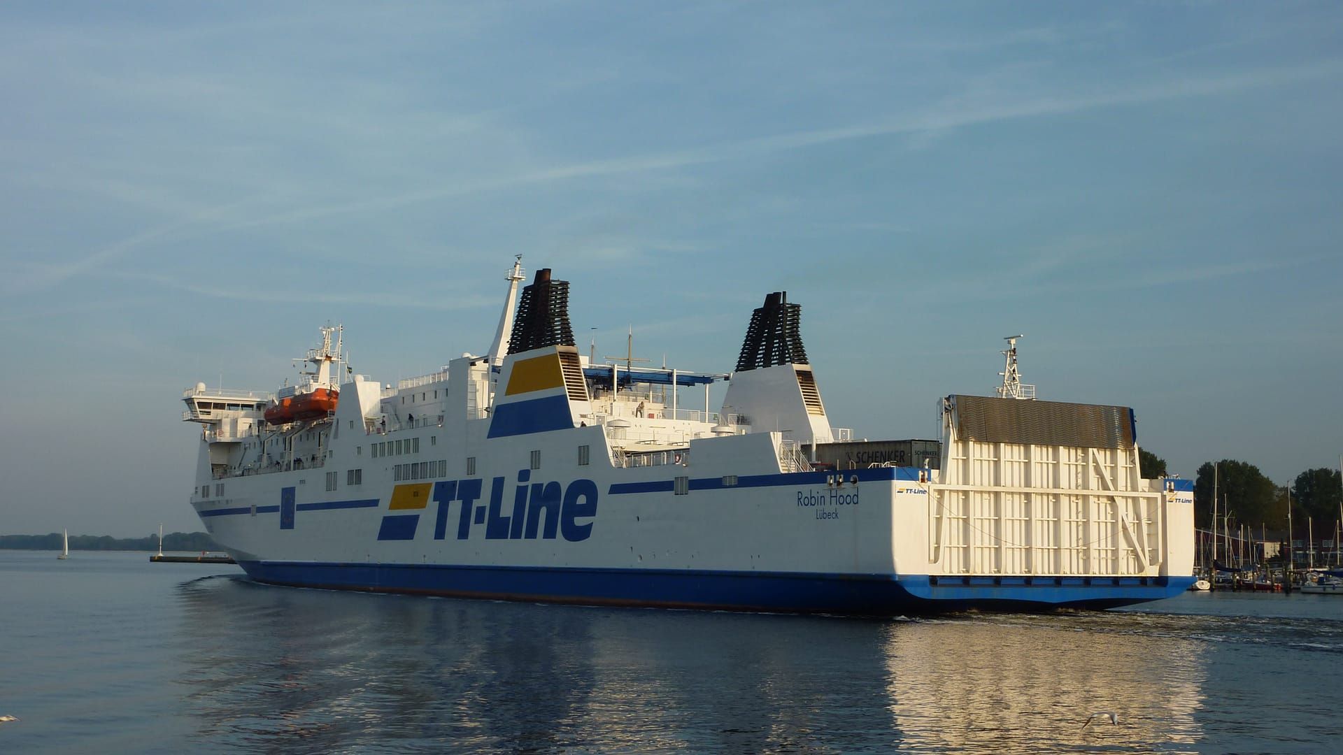 Eine große weiße Fähre der TT-Line gleitet im Abendlicht über die glatte Trave